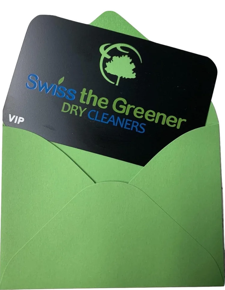A Swiss the Greener Dry Cleaners VIP card partially inserted into a bright green envelope.