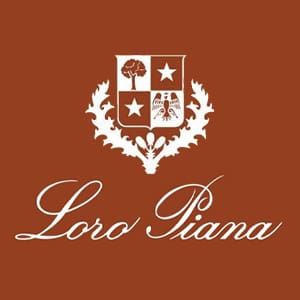 Loro Piana logo featuring a white crest with symbols and decorative elements above the brand name in cursive on a brown background.